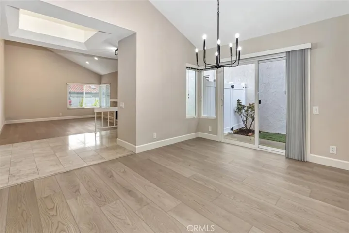 View from dining room towards entry and living room beyond - cheery skyight in entry, sliding door from dining room lets in lots of light