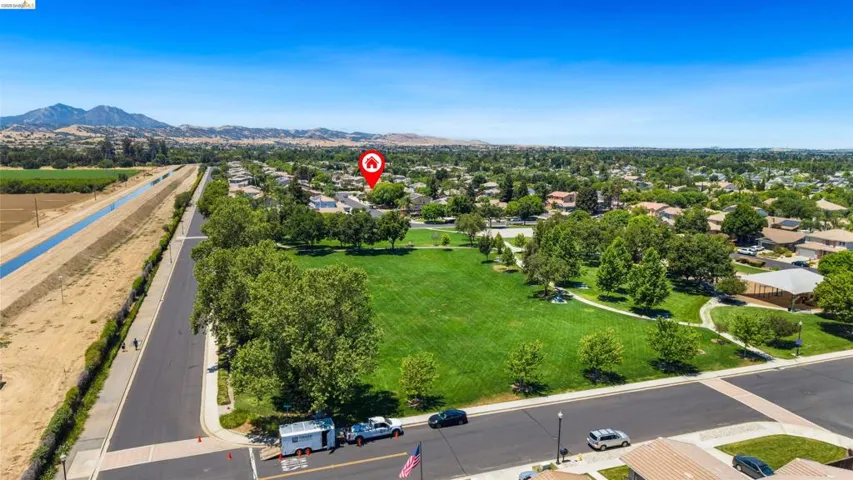 Expansive green parkland with mature trees and paved walking paths
