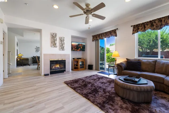 Living area featuring light wood-finish flooring, a ceiling fan with integrated lighting, and recessed lighting
