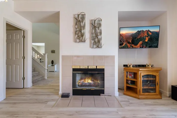 Fireplace featuring a tiled surround and hearth, set against light-toned wood-finish flooring