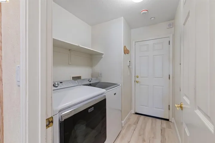 Utility area featuring wood-finish flooring, overhead shelving, and a six-panel exterior door