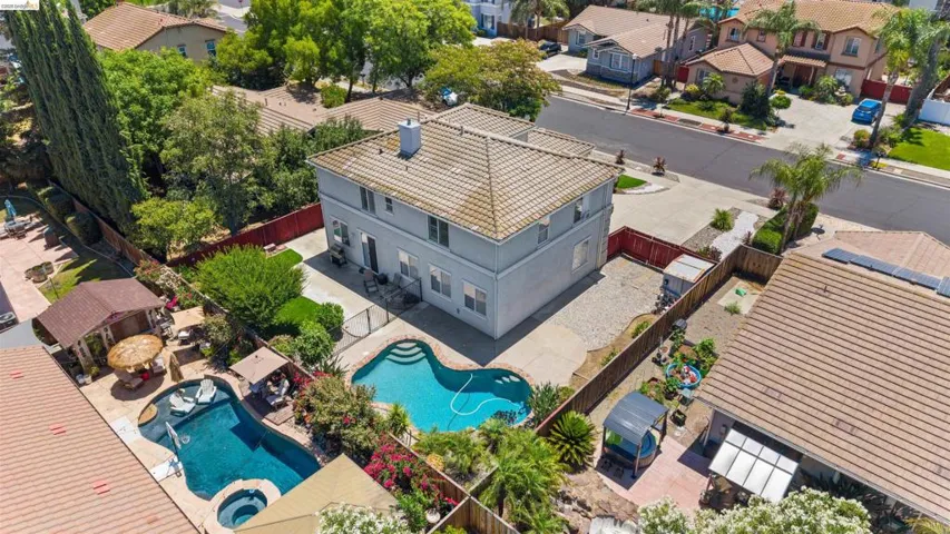 Two-story residence featuring a tile roof, light gray exterior, and multiple rear windows