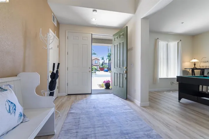 Welcoming entryway featuring light wood-finish flooring and a bright, open double-door entrance