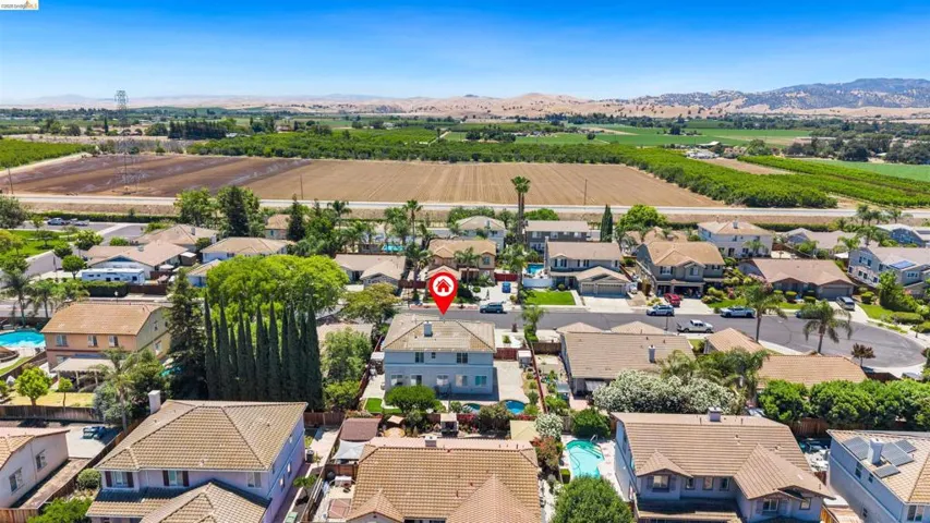 Aerial perspective of a neighborhood with diverse residential structures and surrounding agricultural fields