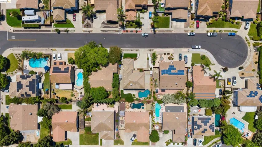 Neighborhood featuring a cul-de-sac street design, multiple private swimming pools, mature landscaping, and numerous rooftop solar panel installations