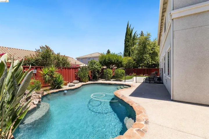 Resort-style pool with integrated steps, stone coping, and expansive concrete patio