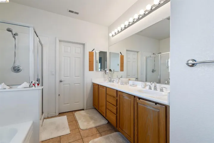 Bathroom featuring a double vanity with wood cabinetry and an expansive wall mirror