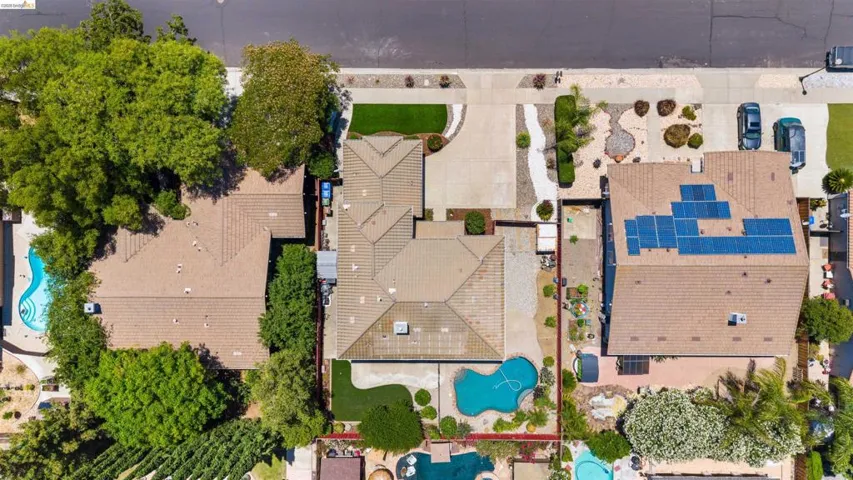 Aerial perspective showcasing a tiled roof, front driveway, and a backyard featuring a swimming pool, artificial turf, and mature landscaping