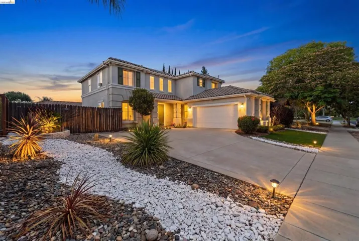Two-story residence featuring a tile roof, an integrated two-car garage, and well-maintained landscaping