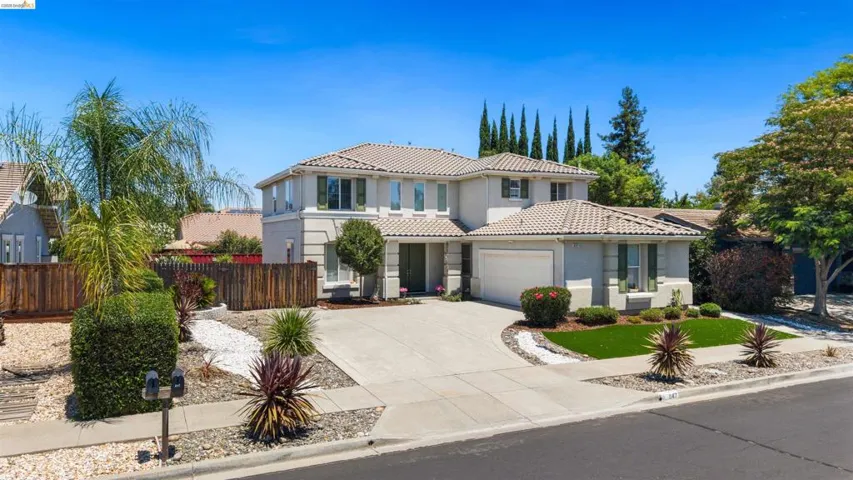 Two-story residence featuring a tile roof, an integrated two-car garage, and a concrete driveway