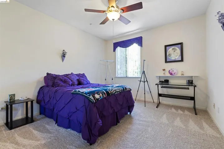 Carpeted room featuring a ceiling fan with integrated lighting, a window with vertical blinds, and neutral wall tones