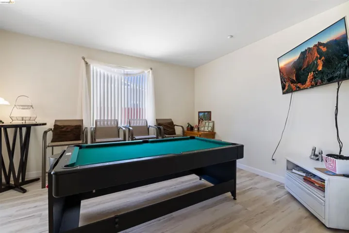 Spacious room featuring light-toned walls and wood-finish flooring