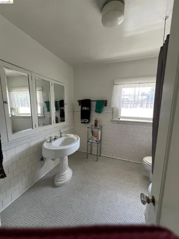 Bathroom featuring white subway tile wainscoting, pedestal sink, and herringbone pattern floor tile