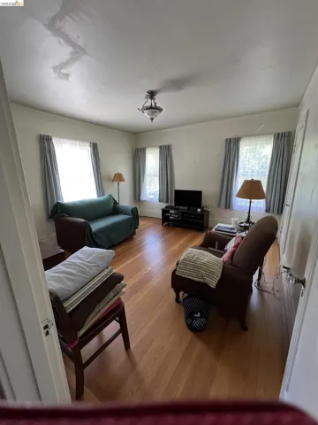 Hardwood flooring throughout, featuring multiple windows with natural light, and a ceiling-mounted light fixture
