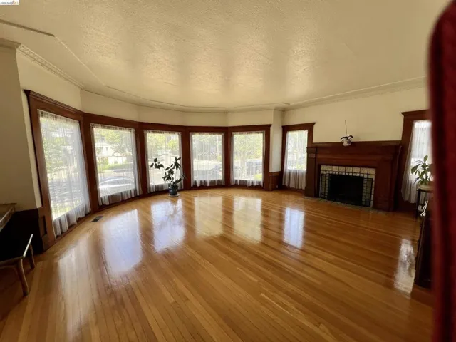 Spacious room featuring rich wood-finish flooring and an ornate wood fireplace surround with tile accents