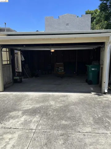 Spacious garage with a concrete floor, overhead lighting, and an open garage door