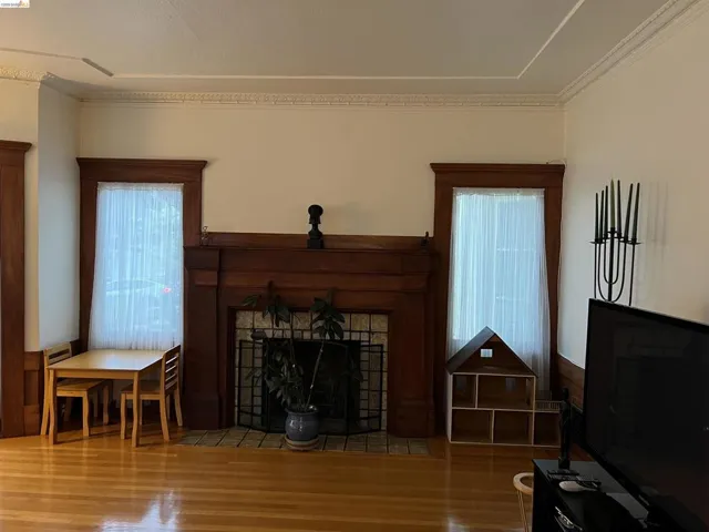 Hardwood flooring throughout featuring a decorative crown molding, and substantial wood trim around windows and doorways