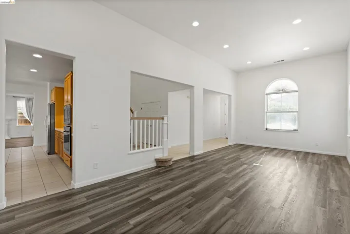 Spacious room featuring wood-finish flooring, recessed lighting, and a vaulted ceiling