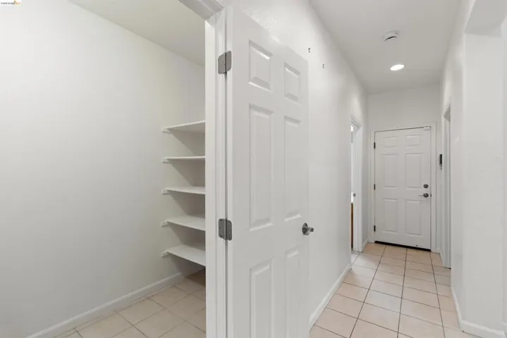 Hallway featuring neutral-toned tile flooring, recessed lighting, and a paneled entry door