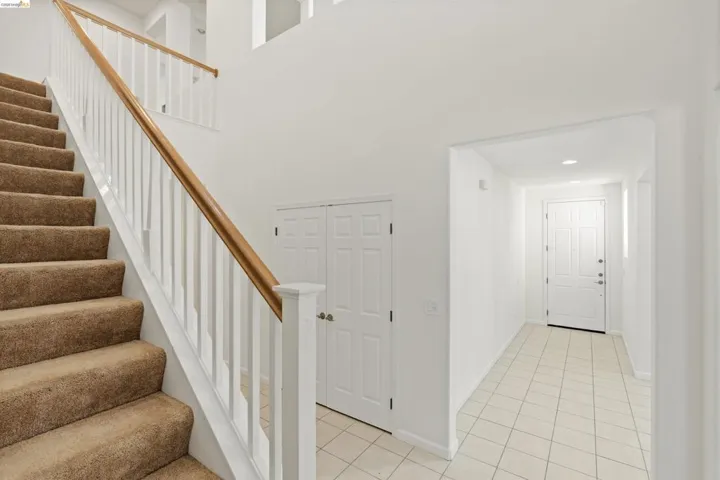 Carpeted staircase with white balusters and a wood-finish handrail