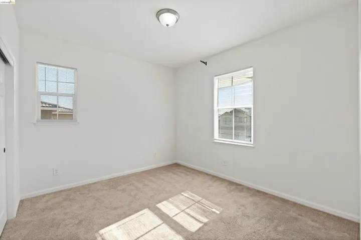 Neutral white walls, two window openings, and a flush mount ceiling fixture