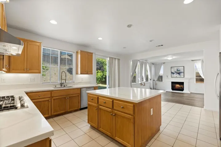 Kitchen featuring light wood cabinetry, white countertops, stainless steel appliances, and tile flooring
