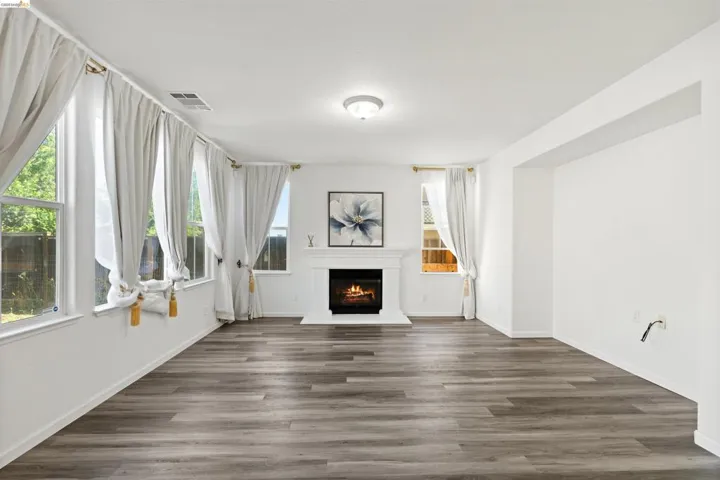 Bright interior space featuring wood-finish flooring, a white mantel fireplace, and multiple windows