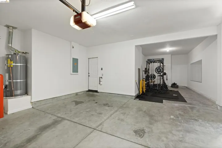 Spacious garage with concrete flooring, a utility door, and overhead lighting