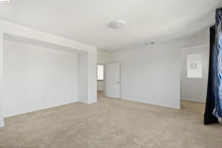 Spacious interior room with neutral carpeting and white painted walls