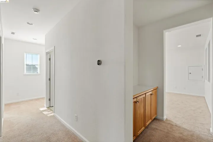 Hallway featuring recessed lighting, light-toned carpeting, a built-in wood-finish cabinet with a light countertop, and white interior doors