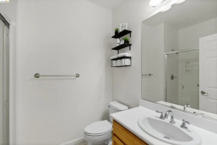 Bathroom featuring a vanity with a white countertop and wood-finish cabinetry, a chrome faucet, and an oversized mirror