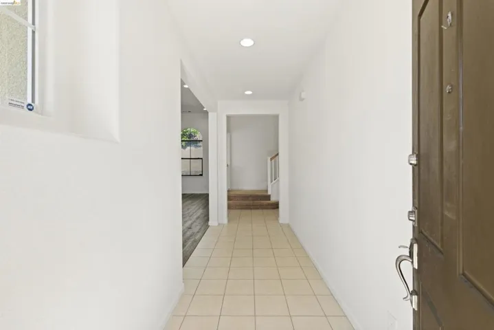 Entryway featuring tile flooring, recessed lighting, and a solid wood-panel door with brushed nickel hardware