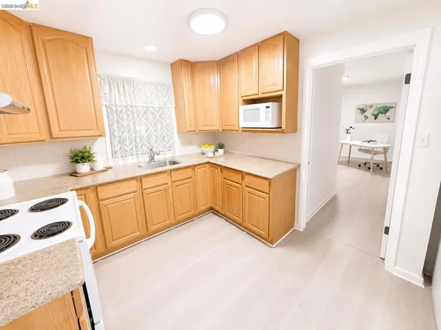 Kitchen featuring wood cabinetry, light-toned countertops, a white tile backsplash, and light wood-finish flooring