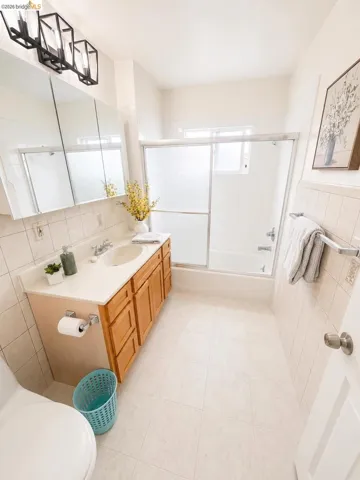 Bathroom featuring a single vanity with wood cabinetry, a built-in sink, and a light-colored countertop