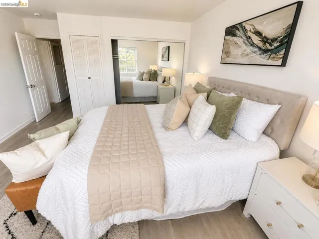 Bedroom featuring light wood-finish flooring, white walls, and a tufted fabric headboard