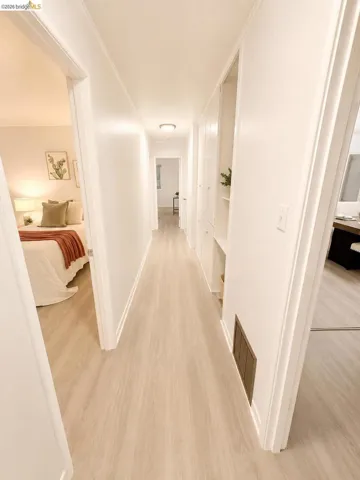 Hallway featuring wood-finish flooring, white walls, and built-in storage cabinetry with open shelving