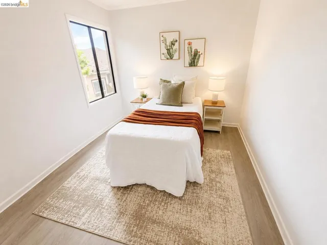 Bright room featuring neutral wall tones, wood-finish flooring, white baseboards, and a modern window frame with dark sashes