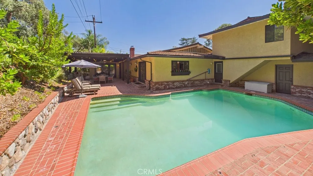Spacious rear yard featuring a swimming pool, a patio area on the left, and a view of bedroom #4 located on the second level above the garage.