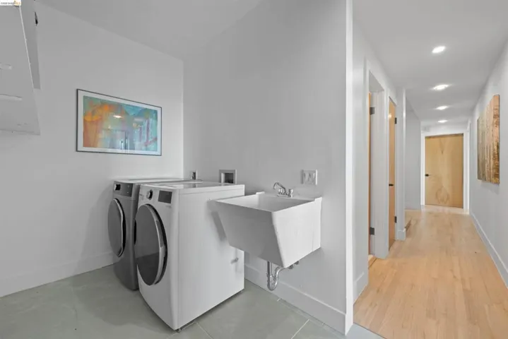 This is down the hall from the Primary_Dedicated laundry area featuring a utility sink, large capacity washer and dryer, and overhead storage