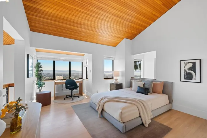 Vaulted wood-finish ceiling, expansive window array, wood-finish flooring, built-in desk, and crisp white walls