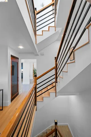 Multi-level stairway featuring light wood treads and risers, complemented by a wood handrail and black metal balusters