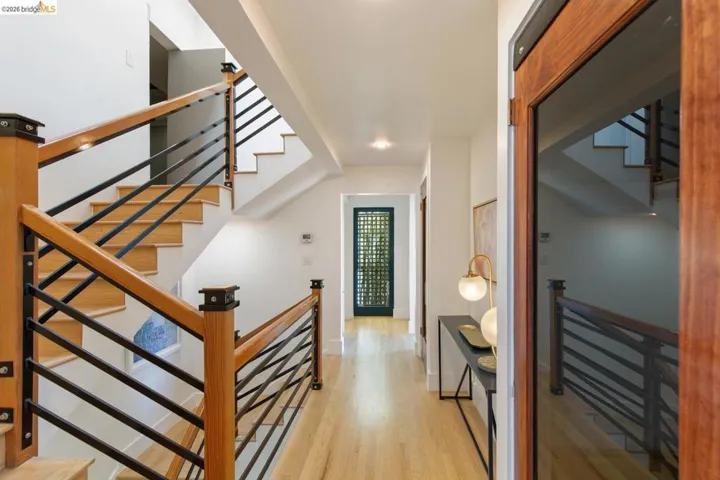 Two-story staircase with light wood-finish treads and risers, complemented by a contemporary wood and black metal railing system