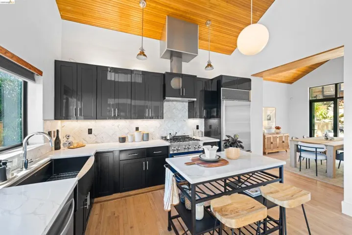 Modern kitchen featuring dark cabinetry, white countertops, and a full-height tile backsplash