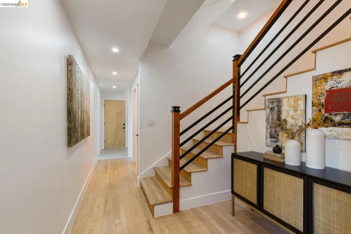 Contemporary staircase featuring natural wood treads and handrails with sleek black metal balusters