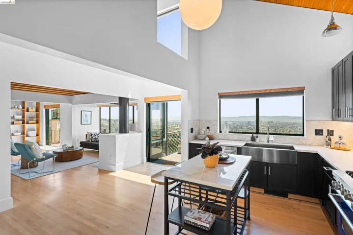 Open-concept living space featuring high vaulted ceilings, light wood-finish flooring, and expansive windows