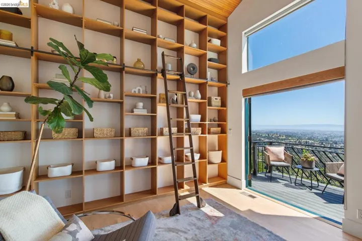 Expansive built-in shelving with a rolling ladder, wood-finish flooring, and a large sliding glass door opening to a balcony with Unobstructed SF Bay Views
