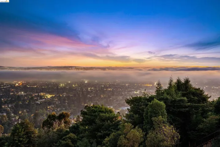 Expansive city vista featuring residential areas, distant hills, and a prominent band of fog