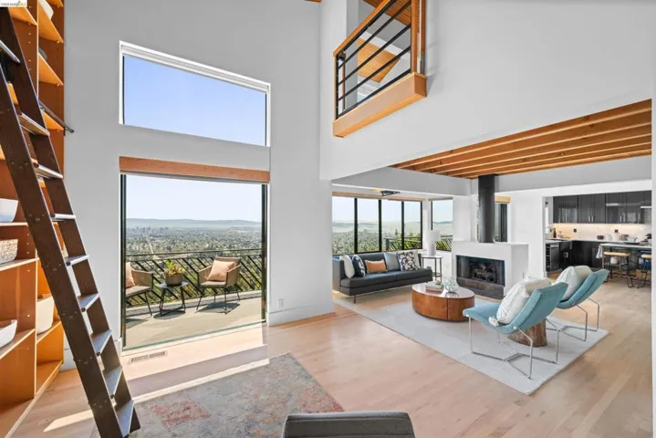 Living room featuring a modern fireplace, light wood-finish flooring, and a balcony with city scenery