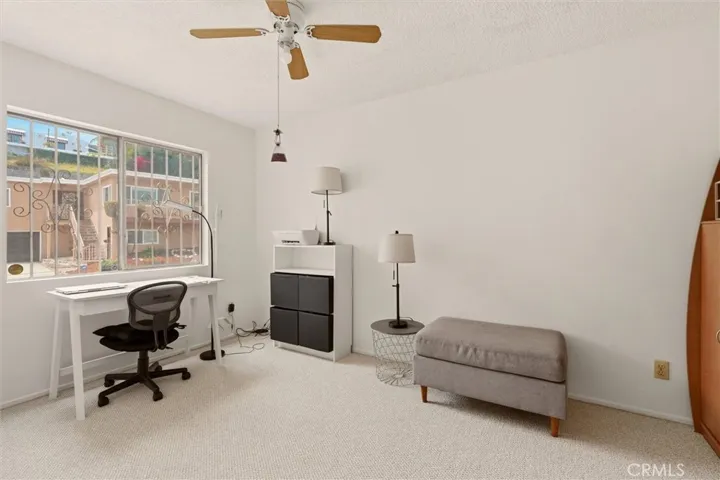 Second bedroom with ceiling fan, Berber carpet, and courtyard-facing window.