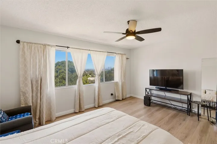 Second bedroom with ceiling fan and hardwood floors.